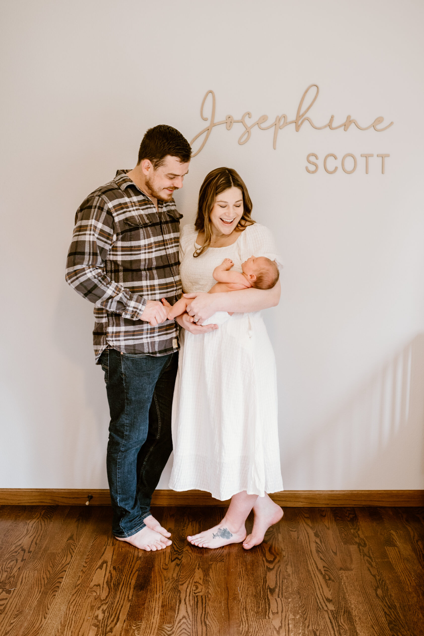 mom, dad, and baby stand in the nursery and admire their newborn