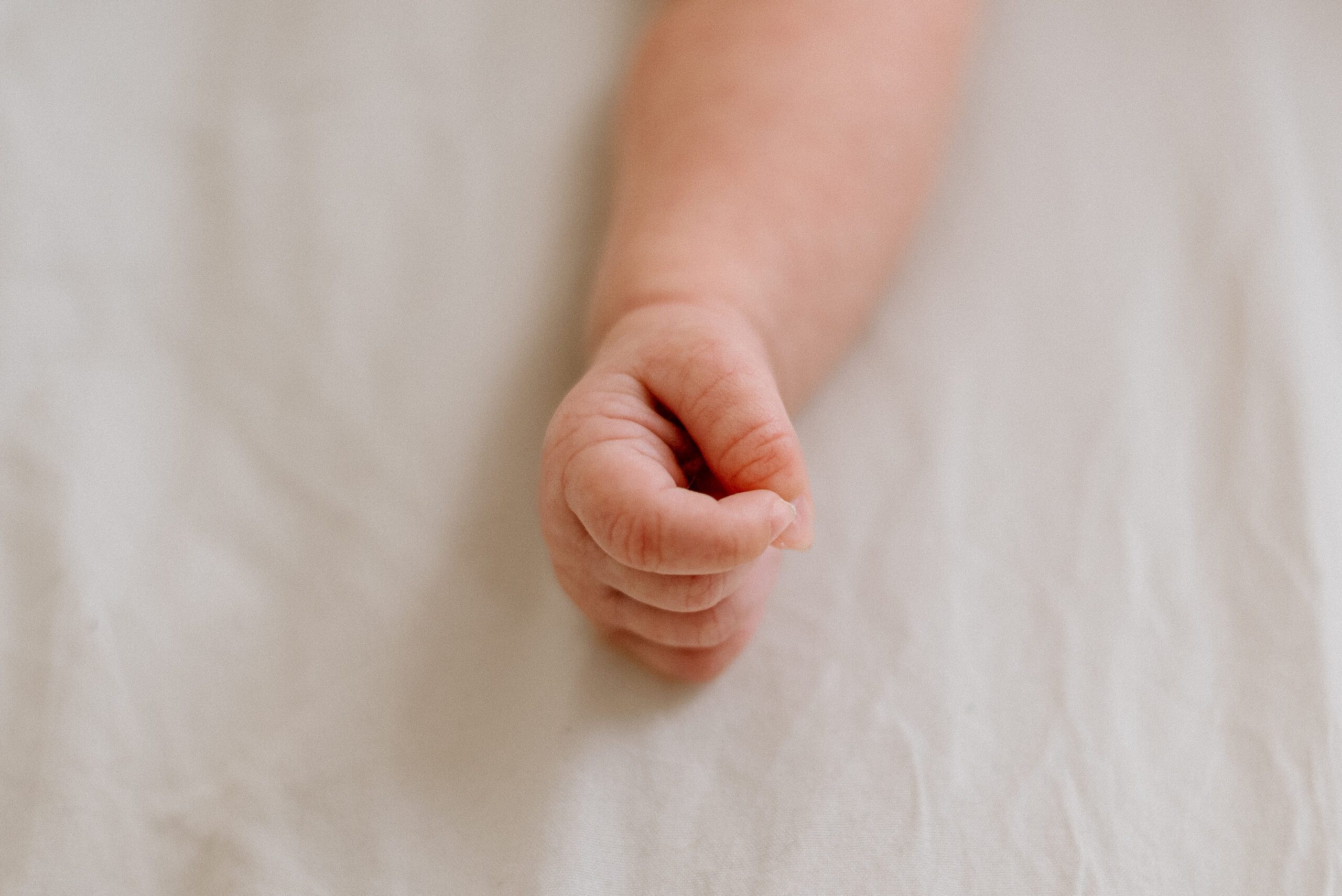 newborn baby hand on a soft white blanket