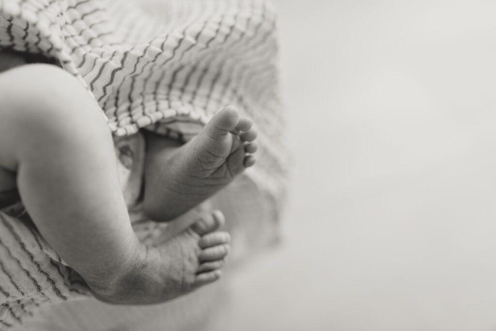 newborn feet poking out of a striped blanket