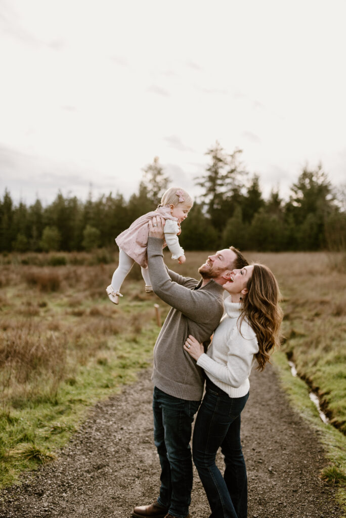 dad holding baby up while mom and dad look up at her